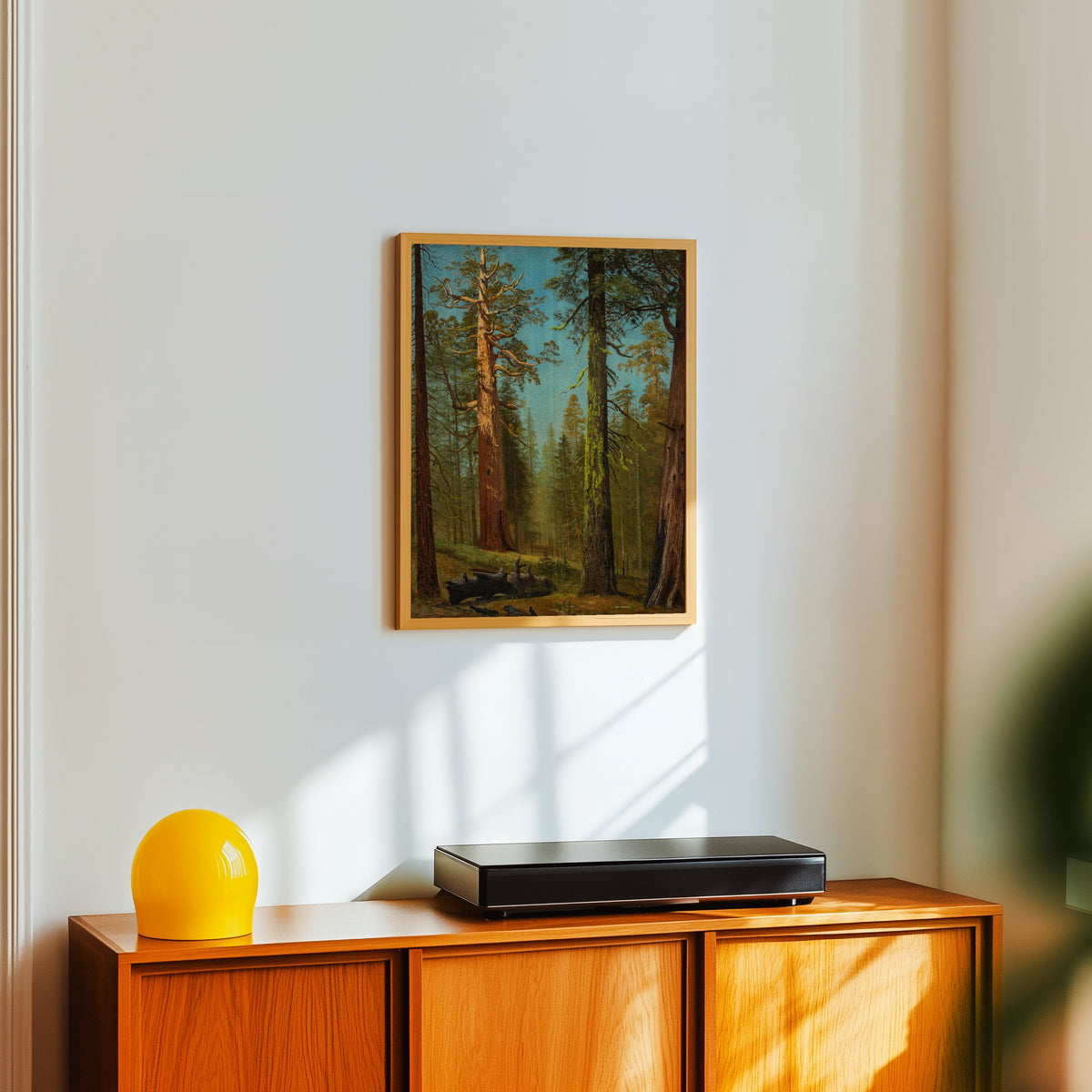 Framed art print of The Grizzly Giant Sequoia, Mariposa Grove, California by Albert Bierstadt, in a light wood frame on a white wall above an orange sideboard