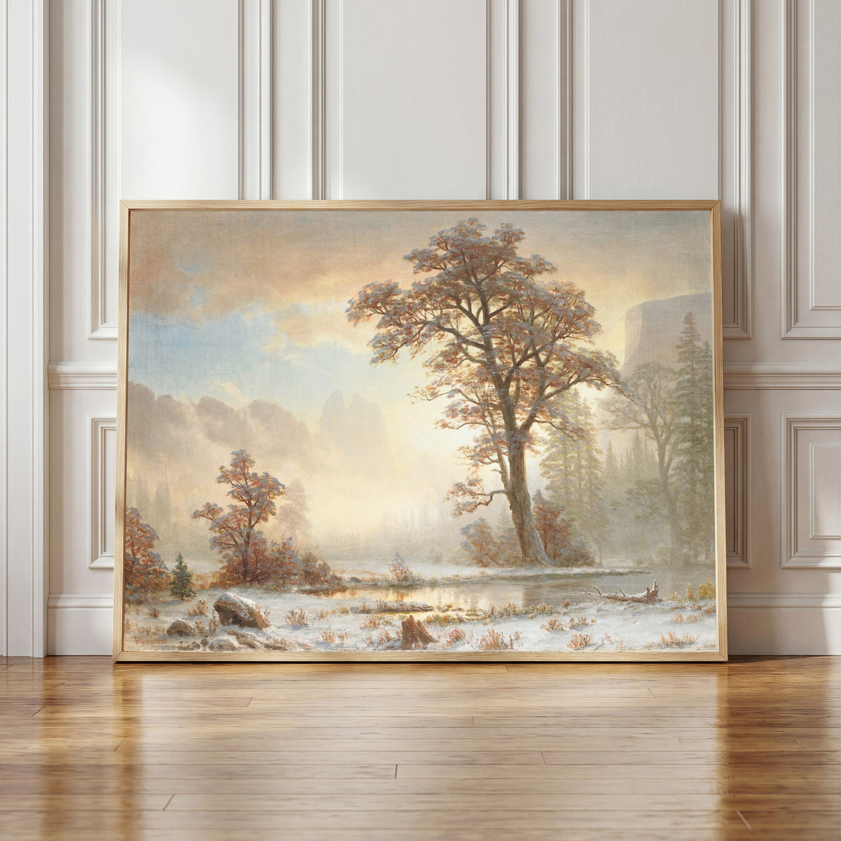 Framed art print of First Snowfall of the Year by Albert Bierstadt, in a light wood frame leaning against a panelled white wall