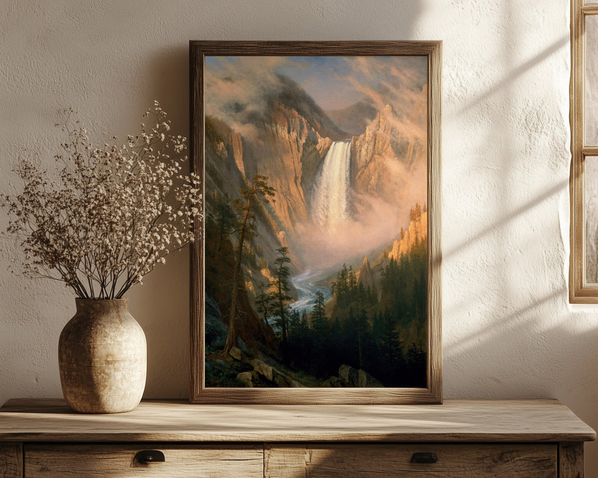 Framed art print of Yellowstone Falls by Albert Bierstadt, in a dark wood frame leaning on a rustic console beside dried flowers