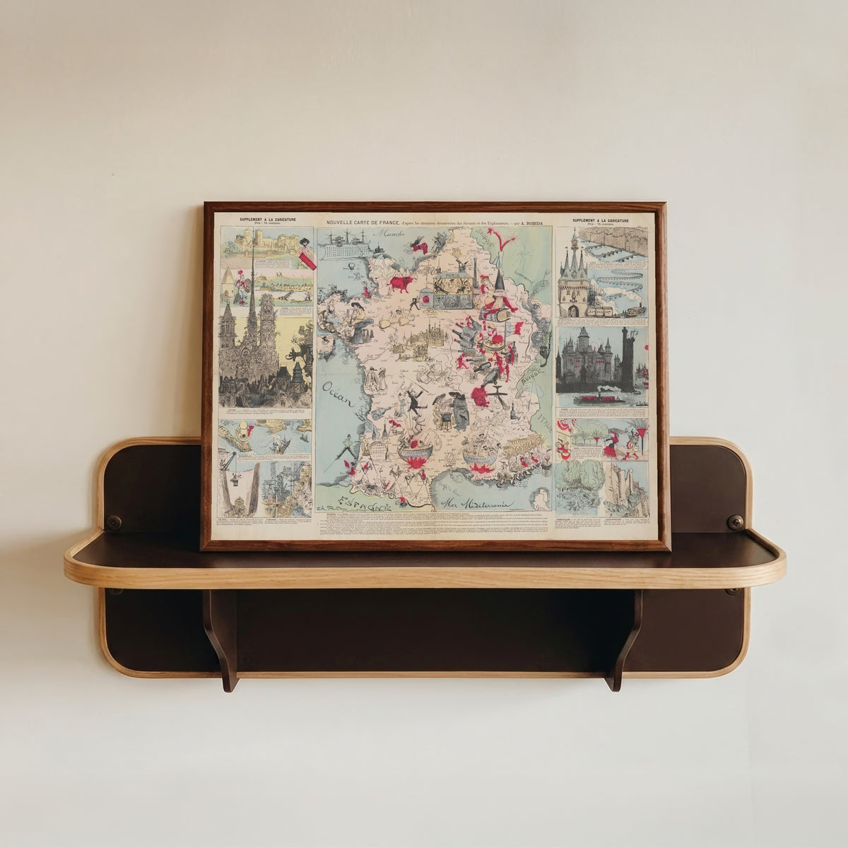 Framed art print of New Map of France, After the Latest Discoveries of the Scientists and… by Albert Robida, in a dark wood frame resting on a wall shelf