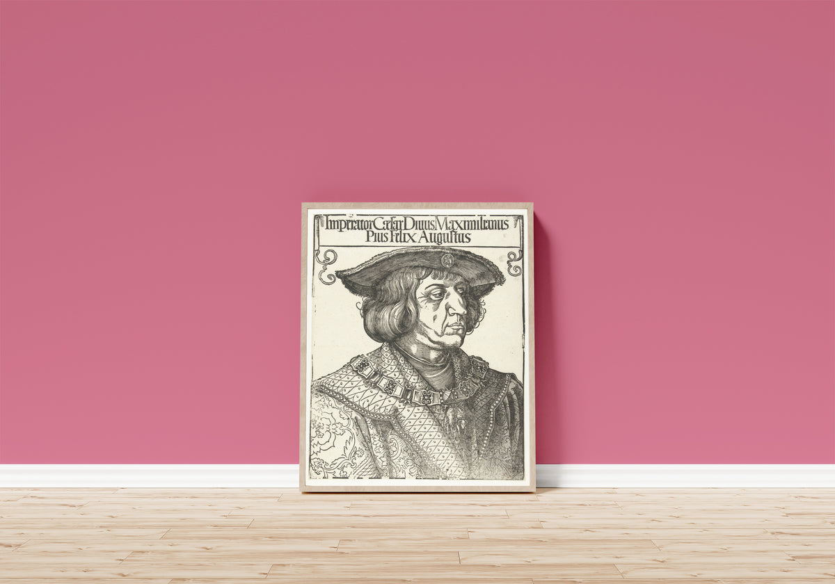 Framed art print of Emperor Maximilian I by Albrecht Dürer, in a light wood frame leaning on a pink wall above a wooden floor