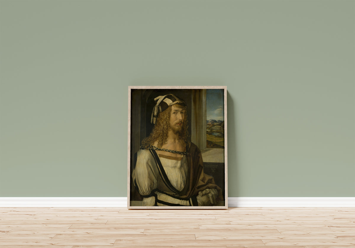 Framed art print of Self-Portrait by Albrecht Dürer, in a light wood frame leaning on a sage green wall above a wooden floor