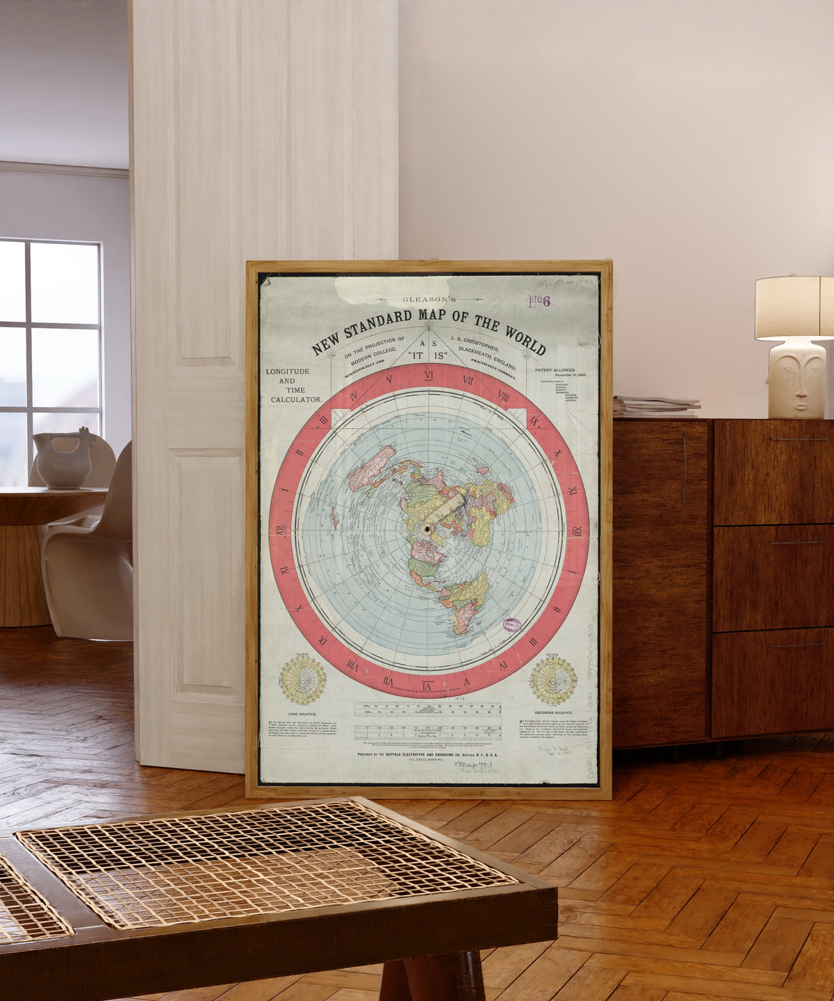 Framed art print of Gleason's New Standard Map of the World by Alexander Gleason, in a light wood frame leaning in a warm room with a parquet floor