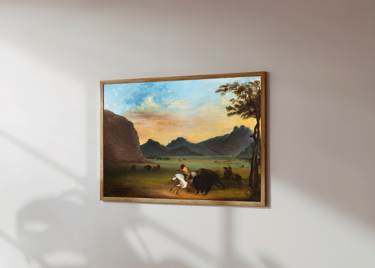 Framed art print of Buffalo Hunt by Alfred Jacob Miller, in a light wood frame on a sunlit white wall, seen at a slight angle