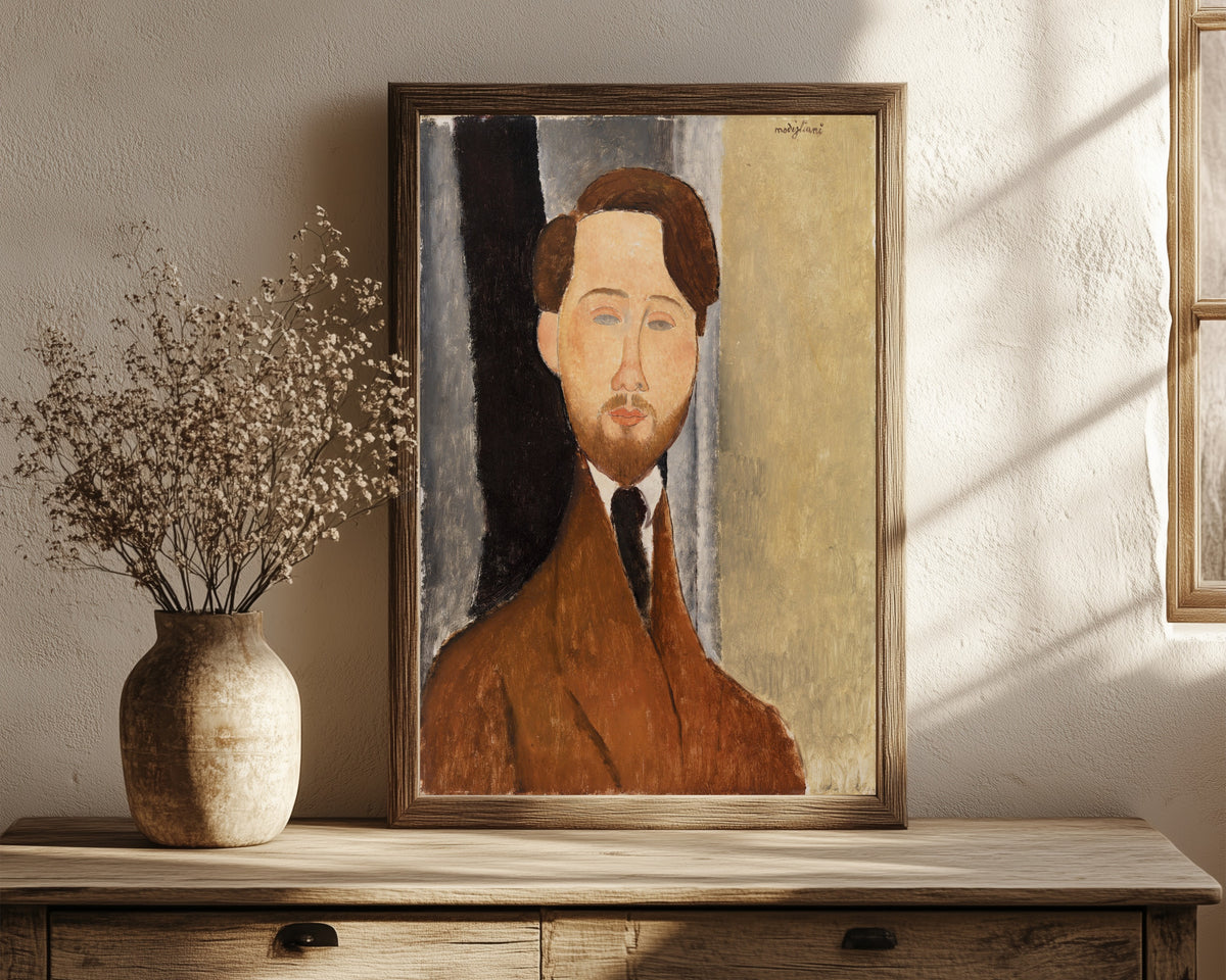 Framed art print of Léopold Zborowski by Amedeo Modigliani, in a dark wood frame leaning on a rustic console beside dried flowers