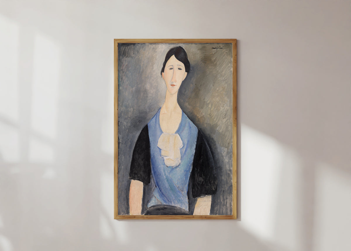 Framed art print of Young Woman in Blue by Amedeo Modigliani, in a light wood frame on a sunlit white wall