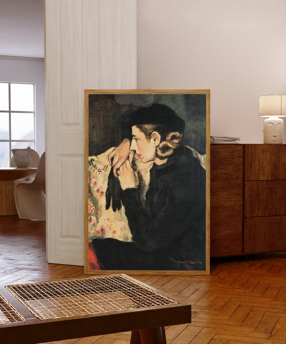 Framed art print of Denise Prouteaux (1932) by Amrita Sher-Gil, in a light wood frame leaning in a warm room with a parquet floor
