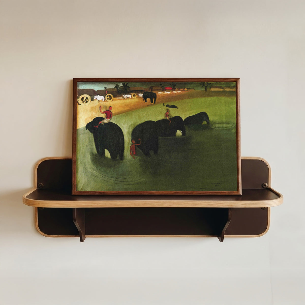 Framed art print of Elephants Bathing in a Green Pool (1938) by Amrita Sher-Gil, in a dark wood frame resting on a wall shelf
