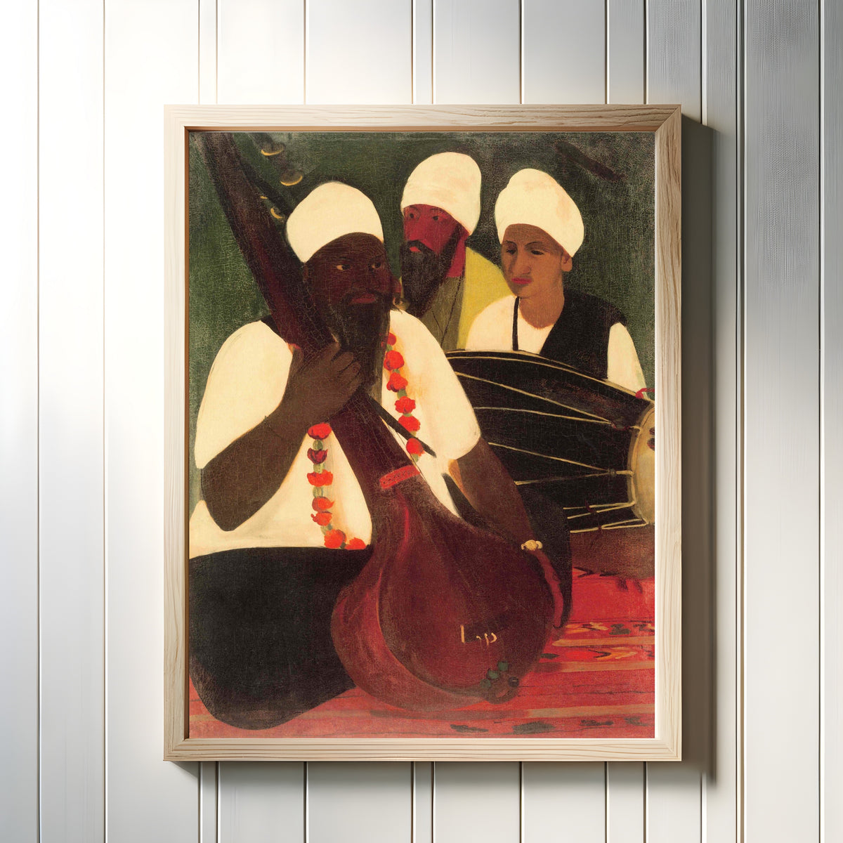 Framed art print of Musicians (1940) by Amrita Sher-Gil, in a light wood frame on a white panelled wall
