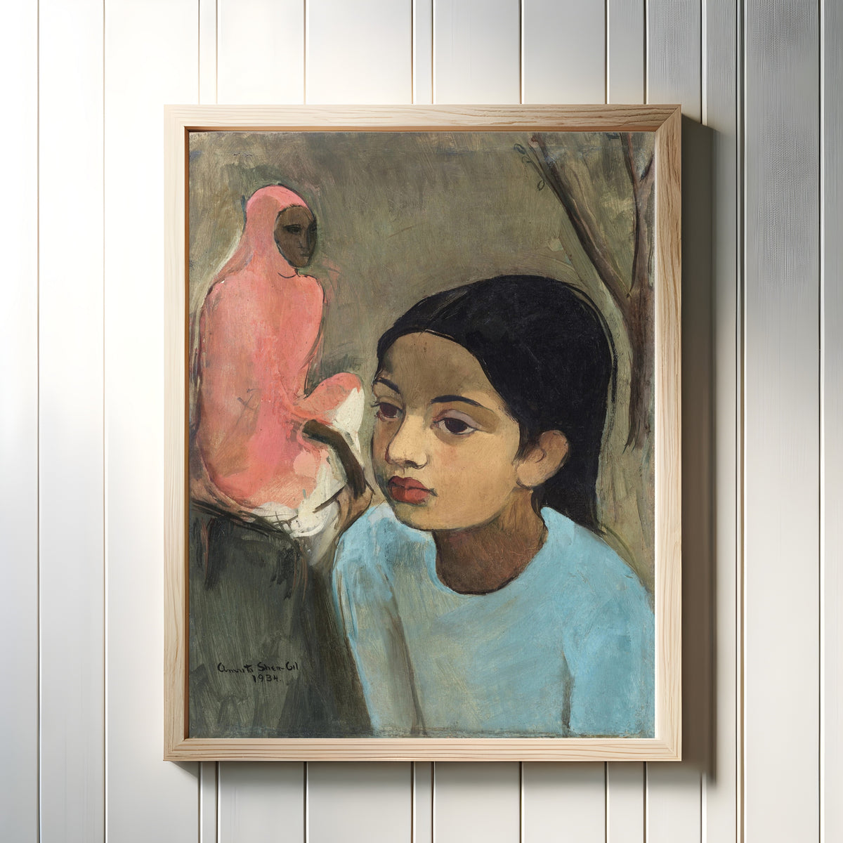 Framed art print of The Little Girl in Blue (1934) by Amrita Sher-Gil, in a light wood frame on a white panelled wall