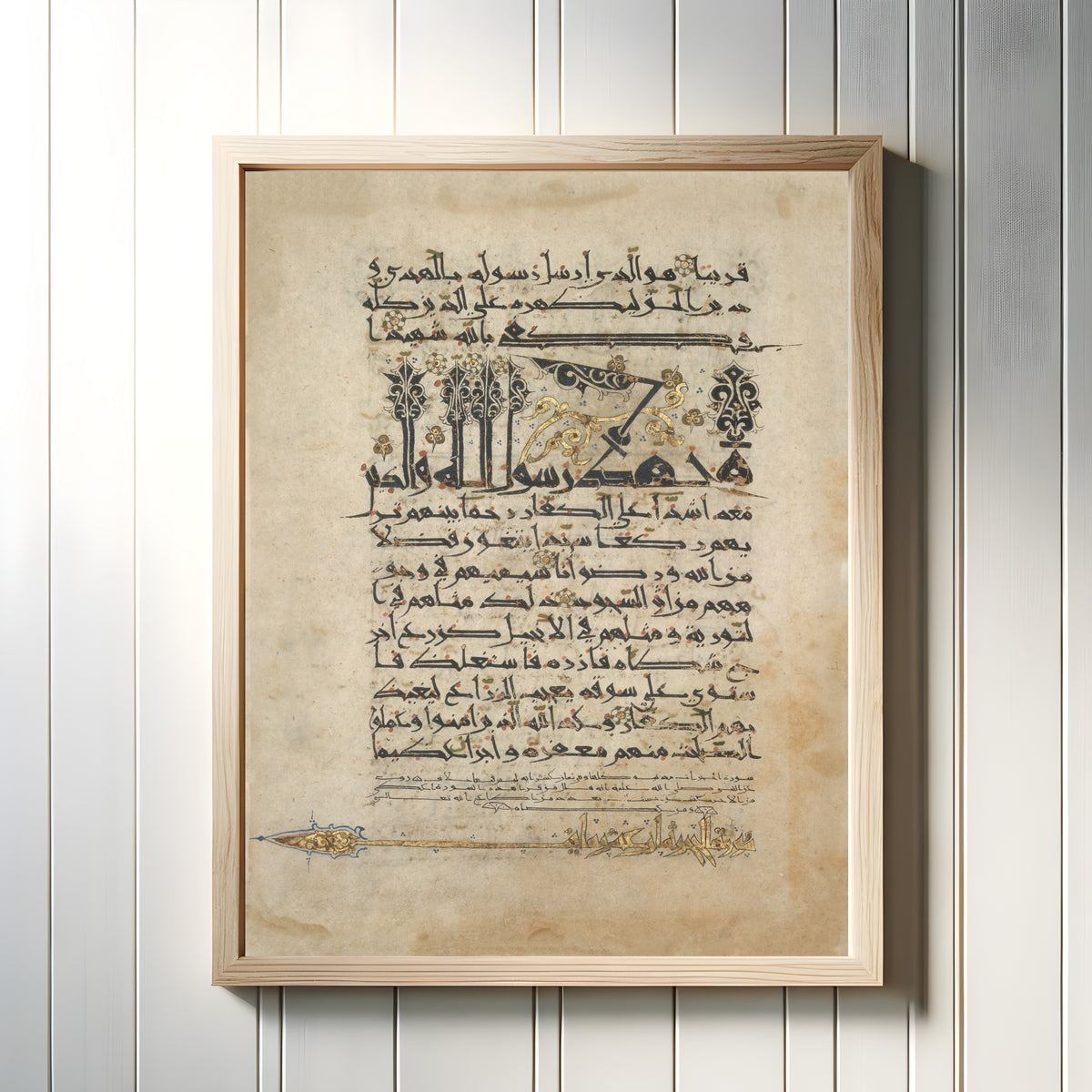 Framed art print of Folios from a Qur'an Manuscript in Floriated "New Style" Script, in a light wood frame on a white panelled wall