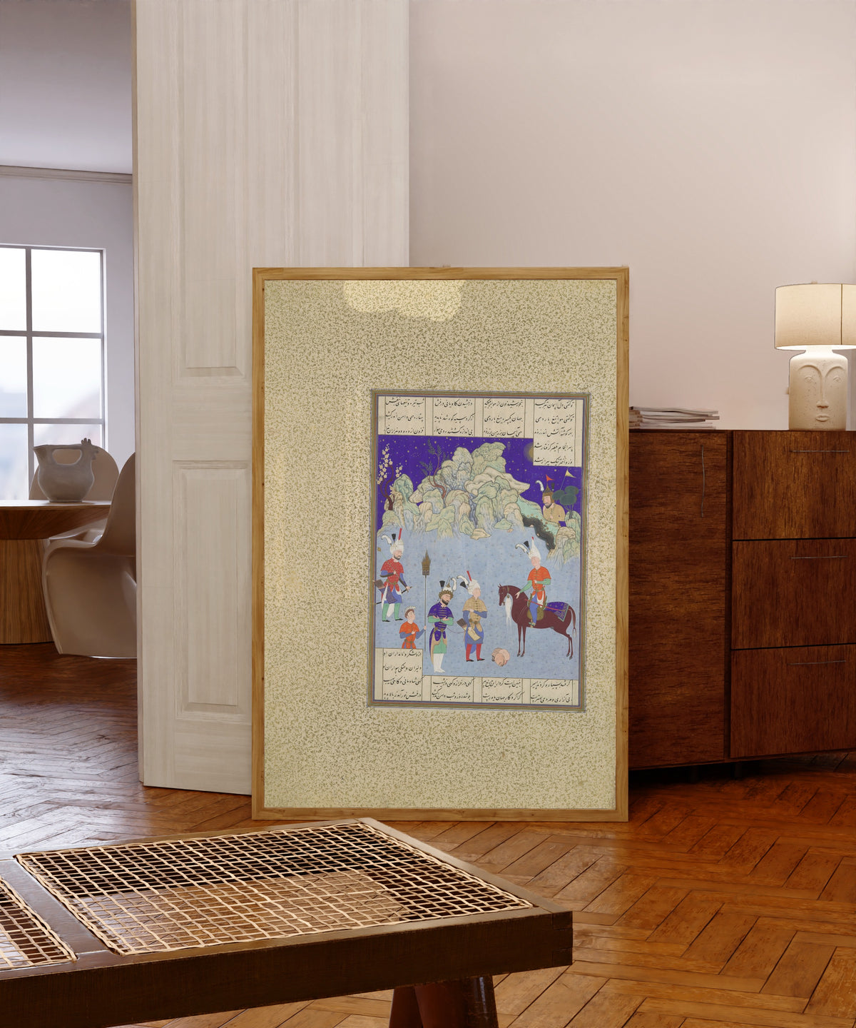 Framed art print of Shahnama of Shah Tahmasp: Caesar Captive… by Aqa Mirak (attributed), in a light wood frame leaning in a warm room with a parquet floor