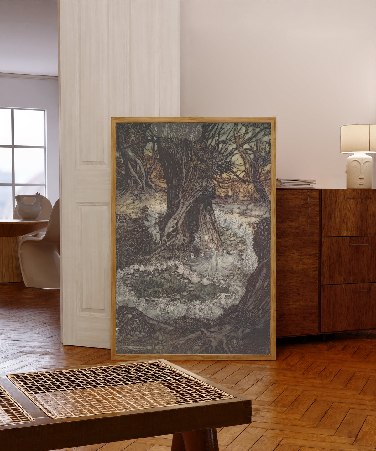 Framed art print of Come, Now a Roundel by Arthur Rackham, in a light wood frame leaning in a warm room with a parquet floor