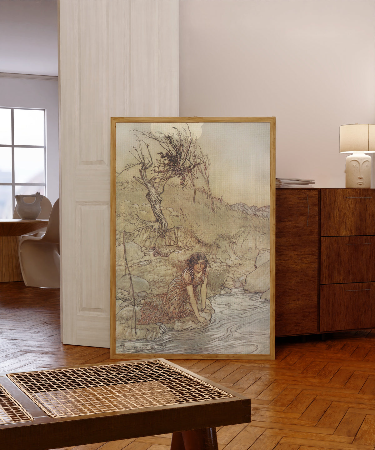 Framed art print of Hermia by Arthur Rackham, in a light wood frame leaning in a warm room with a parquet floor