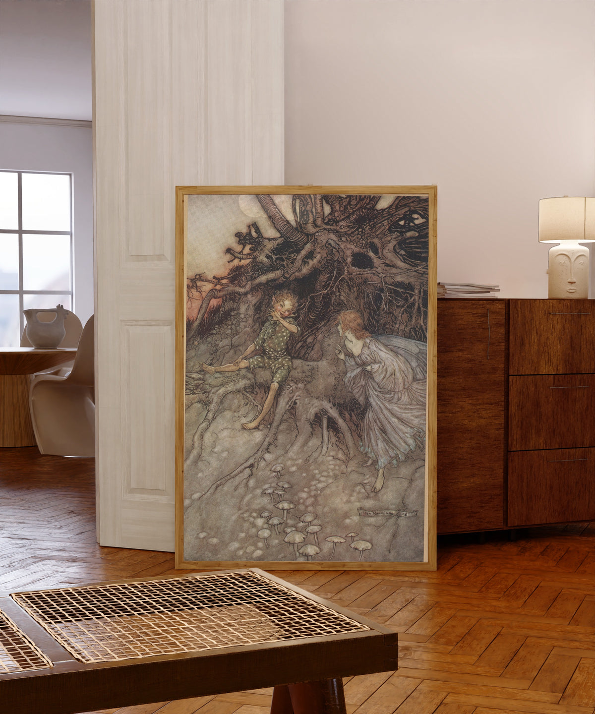 Framed art print of I Am That Merry Wanderer of the Night by Arthur Rackham, in a light wood frame leaning in a warm room with a parquet floor