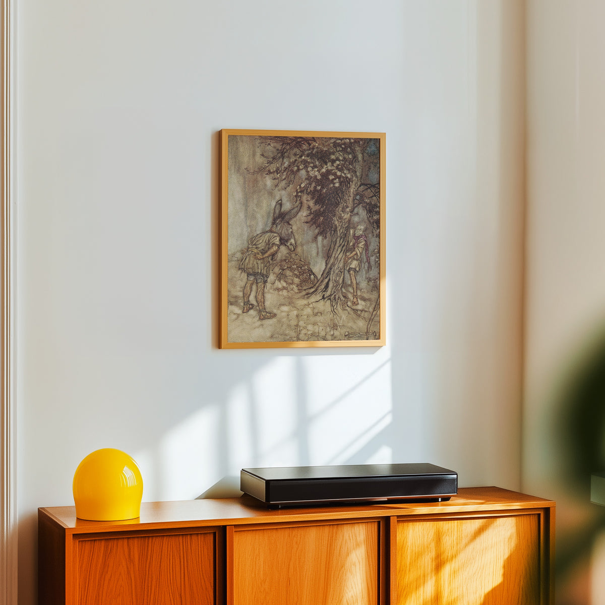 Framed art print of O Bottom, Thou Art Changed! by Arthur Rackham, in a light wood frame on a white wall above an orange sideboard
