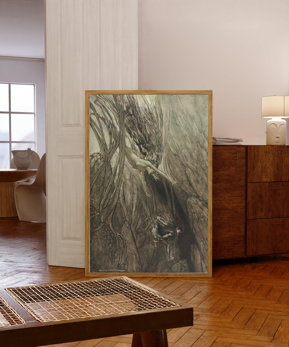 Framed art print of Seize the Despoiler! Rescue the Gold! by Arthur Rackham, in a light wood frame leaning in a warm room with a parquet floor