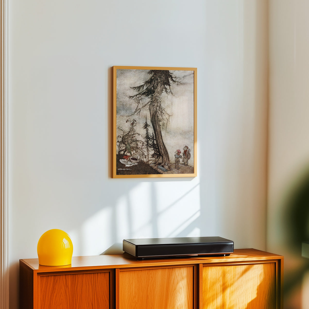 Framed art print of The Fir-Tree and the Bramble by Arthur Rackham, in a light wood frame on a white wall above an orange sideboard