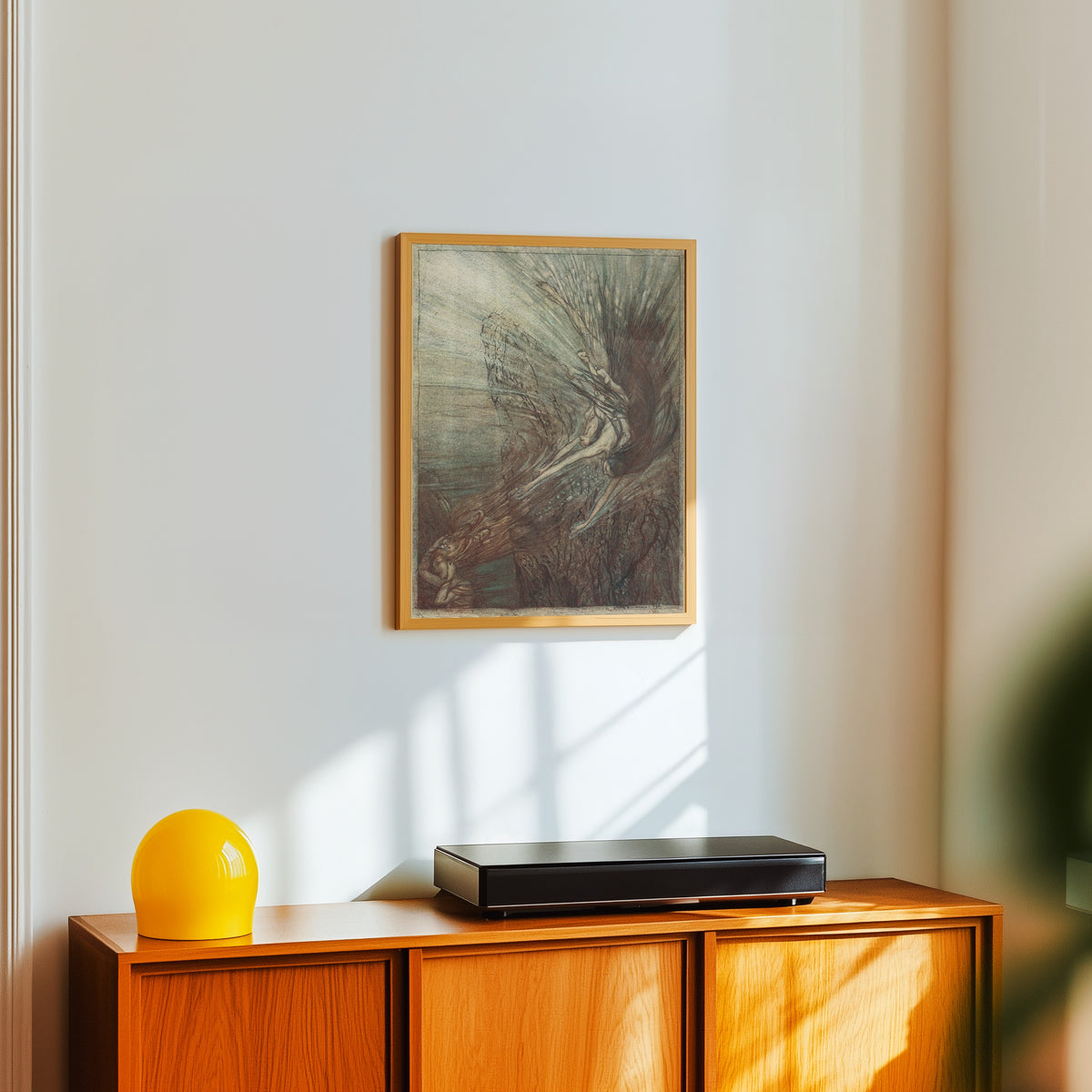 Framed art print of The Frolic of the Rhine-Maidens by Arthur Rackham, in a light wood frame on a white wall above an orange sideboard