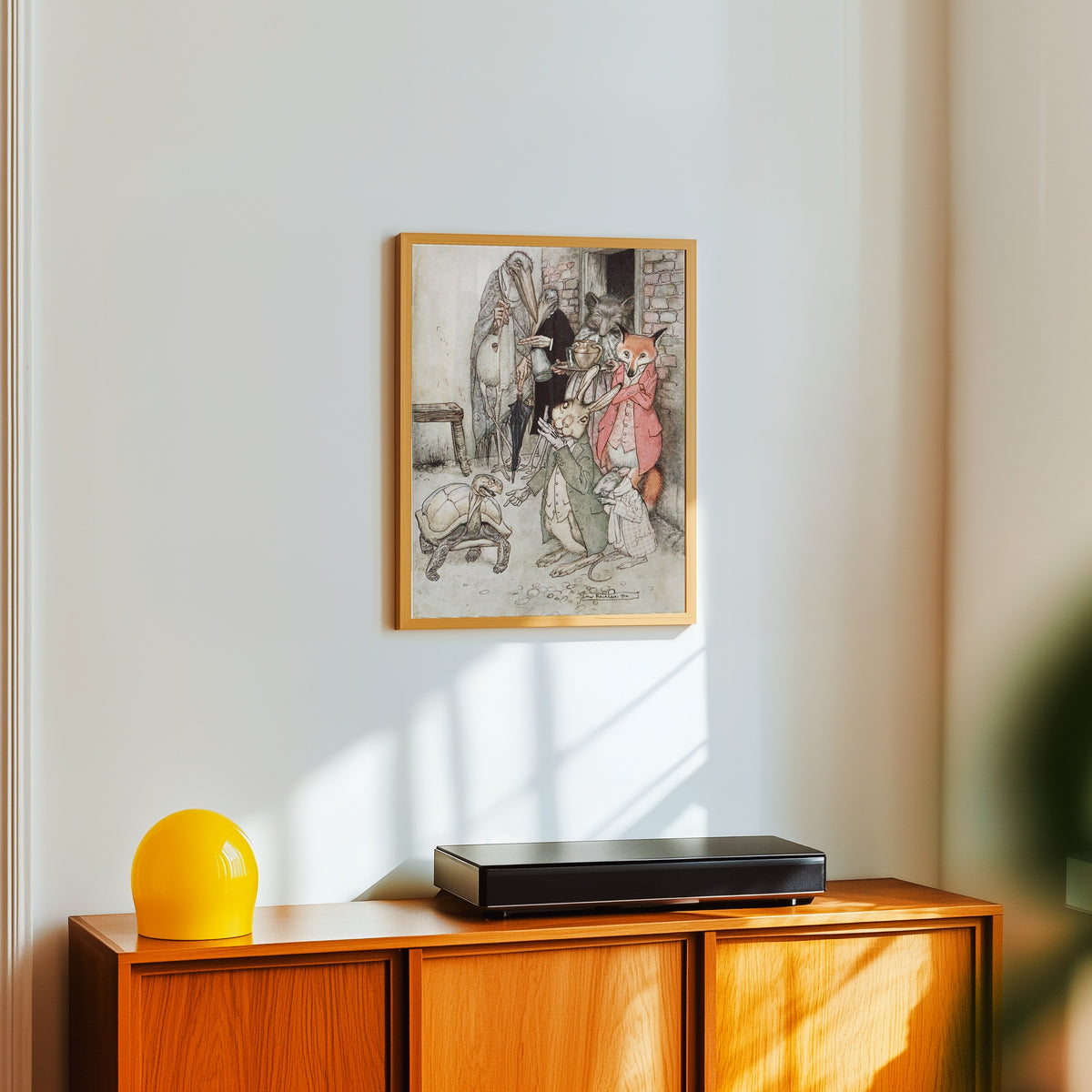 Framed art print of The Hare and the Tortoise by Arthur Rackham, in a light wood frame on a white wall above an orange sideboard