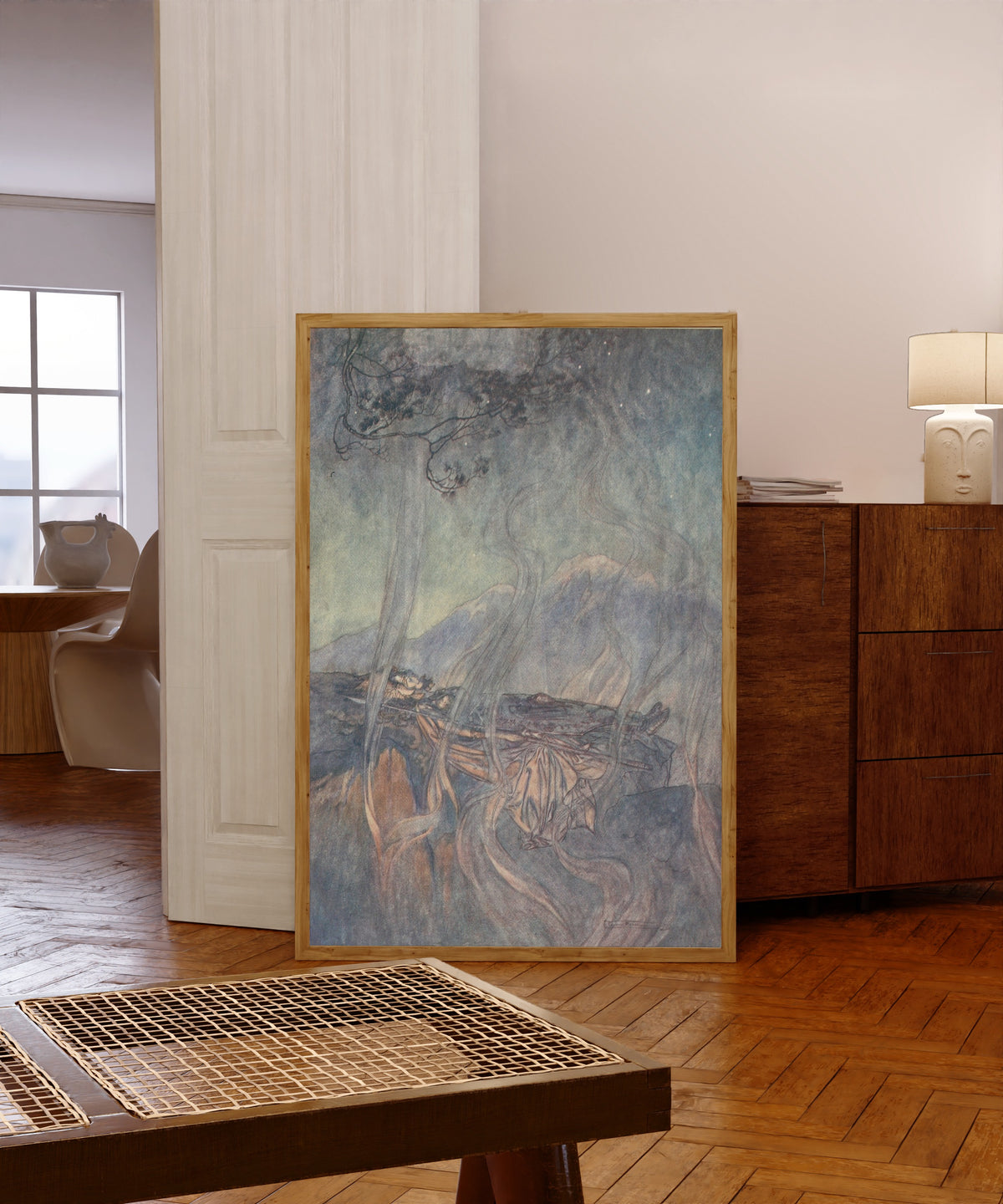 Framed art print of The Sleep of Brünnhilde by Arthur Rackham, in a light wood frame leaning in a warm room with a parquet floor