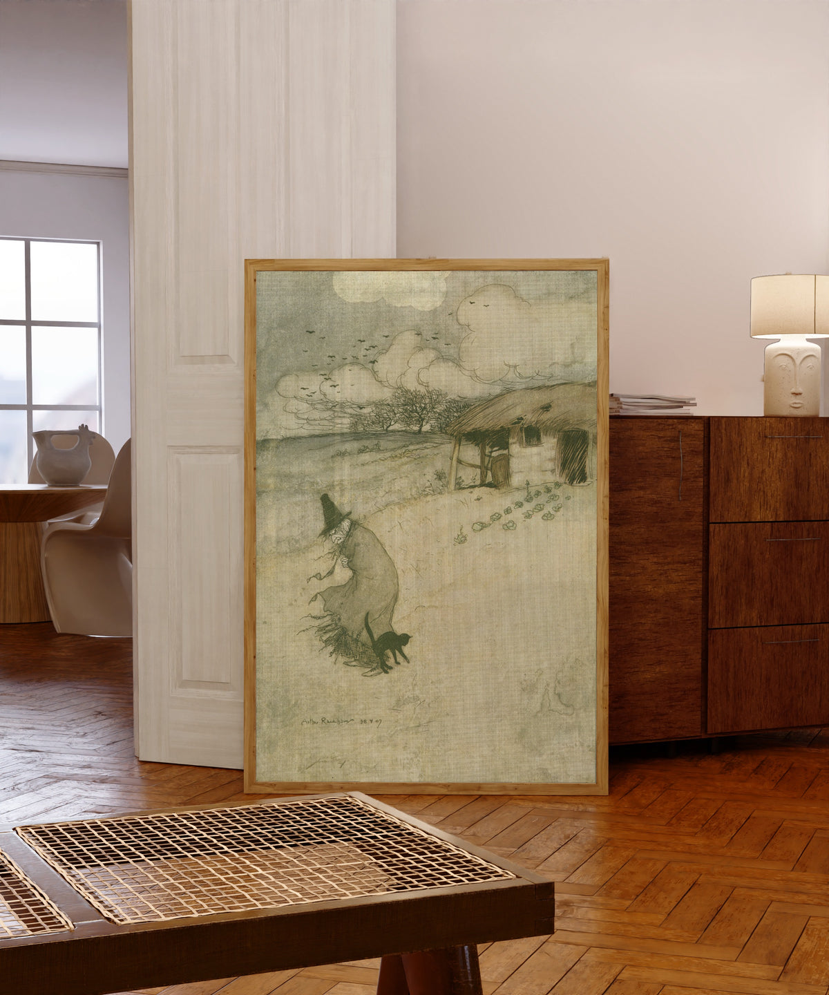 Framed art print of There’s an Old Woman Dwells upon Tappington Moor by Arthur Rackham, in a light wood frame leaning in a warm room with a parquet floor