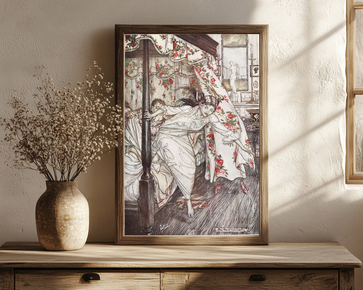 Framed art print of Venus and the Cat by Arthur Rackham, in a dark wood frame leaning on a rustic console beside dried flowers