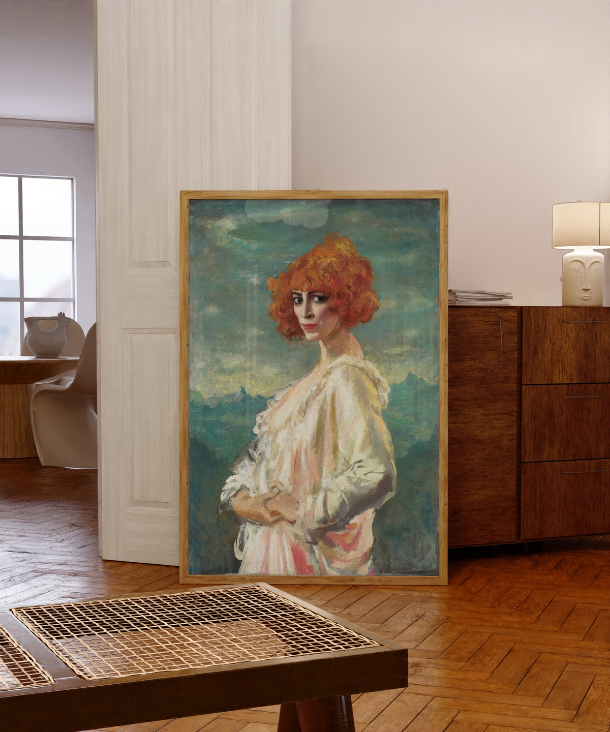 Framed art print of The Marchesa Casati by Augustus John, in a light wood frame leaning in a warm room with a parquet floor
