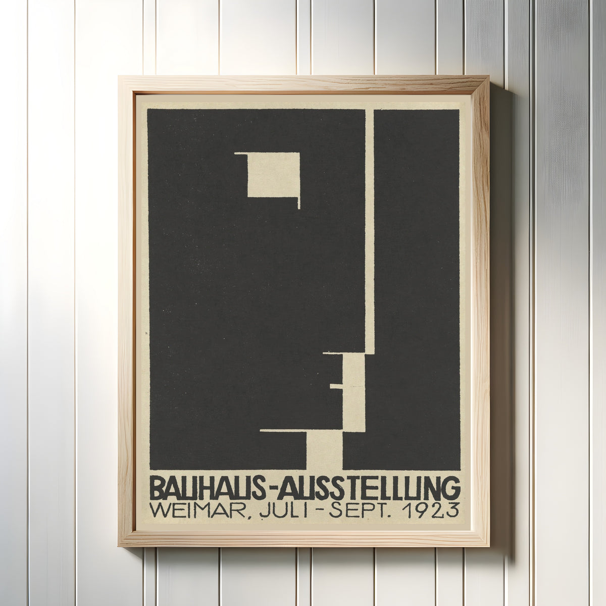 Framed art print of Ausstellung 1923 by Bauhaus, in a light wood frame on a white panelled wall