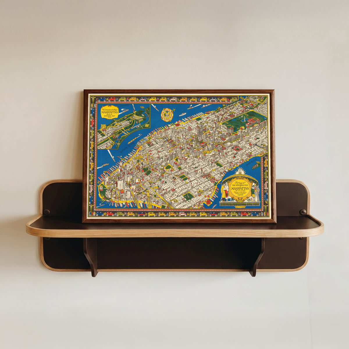 Framed art print of A Map of the Wondrous Isle of Manhattan by C. V. Farrow, in a dark wood frame resting on a wall shelf