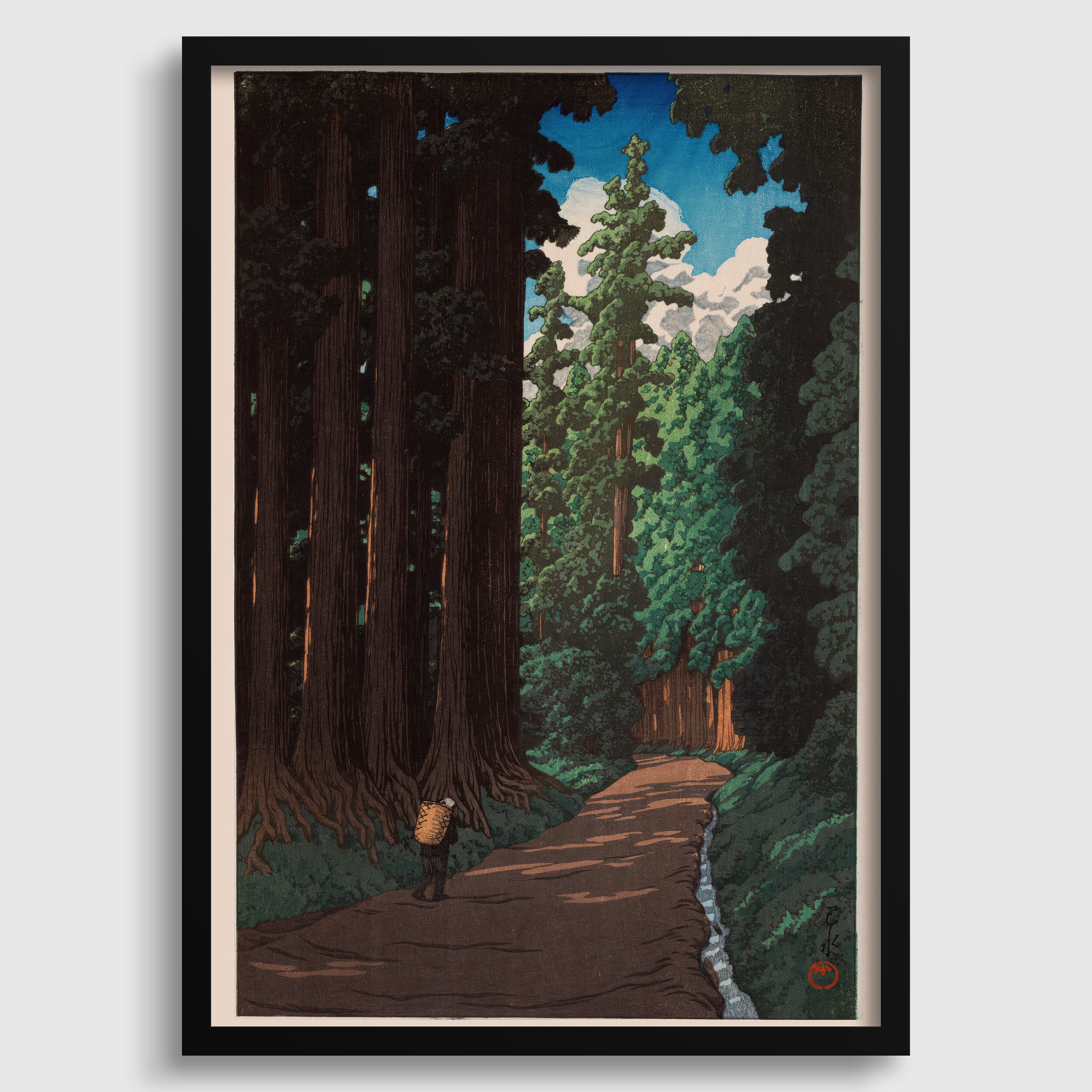 a person walking along a dirt path through a lush, forested area with towering trees on either side.