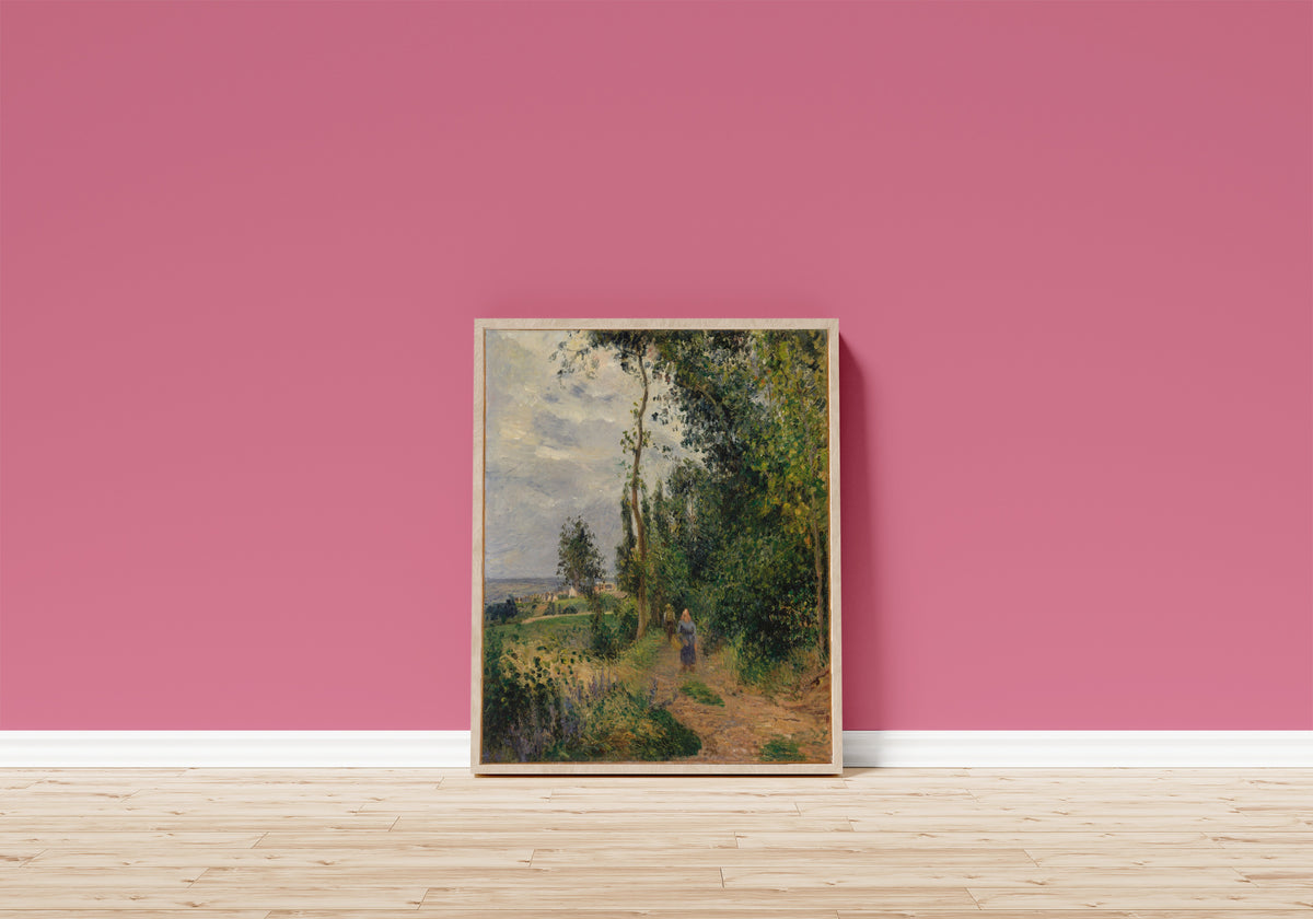 Framed art print of Côte des Grouettes, near Pontoise by Camille Pissarro, in a light wood frame leaning on a pink wall above a wooden floor