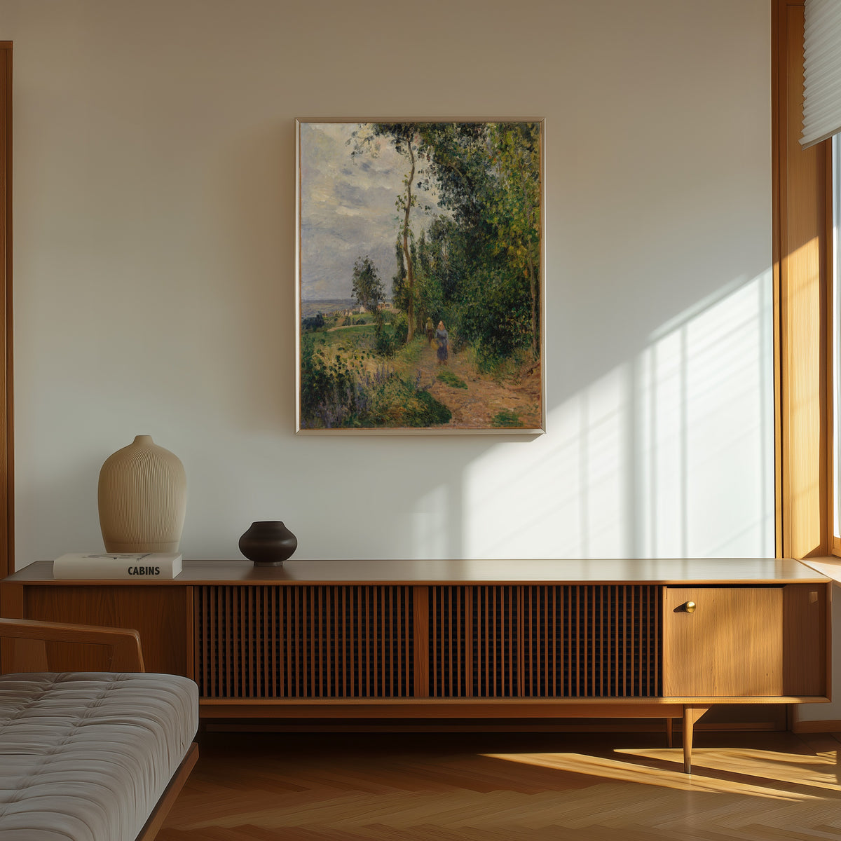Framed art print of Côte des Grouettes, near Pontoise by Camille Pissarro, in a thin light frame on a sunlit wall above a wooden sideboard