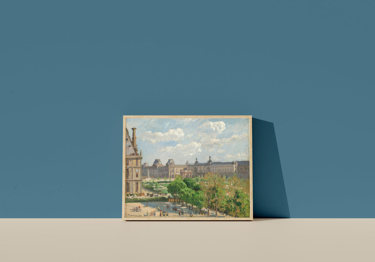 Framed art print of Place du Carrousel, Paris by Camille Pissarro, in a light wood frame leaning on a blue wall