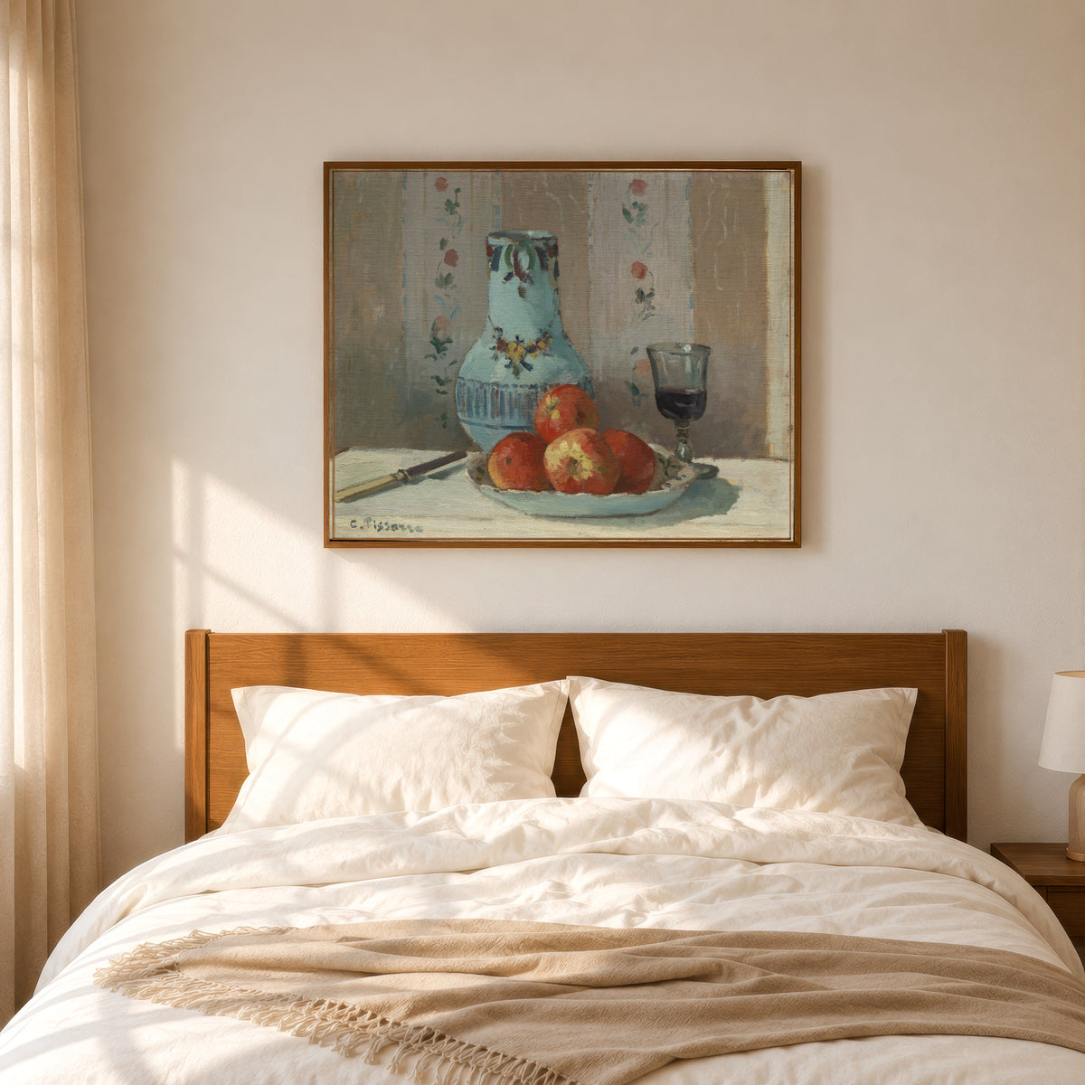 Framed art print of Still Life with Apples and Pitcher by Camille Pissarro, in a slim wood frame above a bed in a sunlit bedroom
