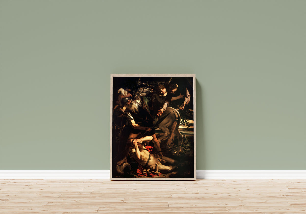 Framed art print of Conversion of St. Paul by Caravaggio, in a light wood frame leaning on a sage green wall above a wooden floor