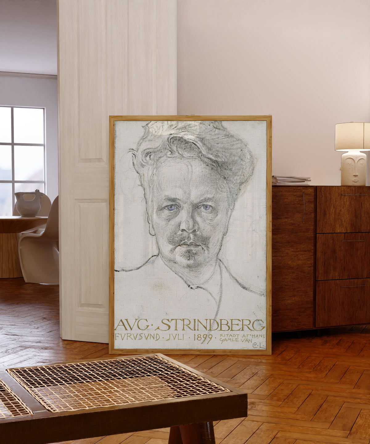 Framed art print of The Author August Strindberg by Carl Larsson, in a light wood frame leaning in a warm room with a parquet floor