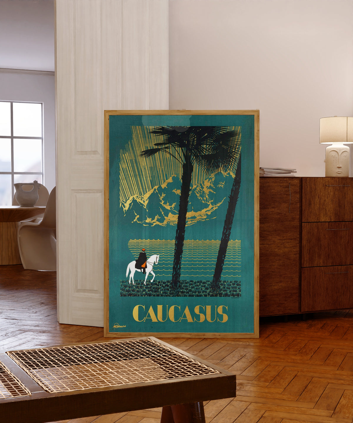 Framed art print of Caucasus by Nikolai Zhukov, in a light wood frame leaning in a warm room with a parquet floor