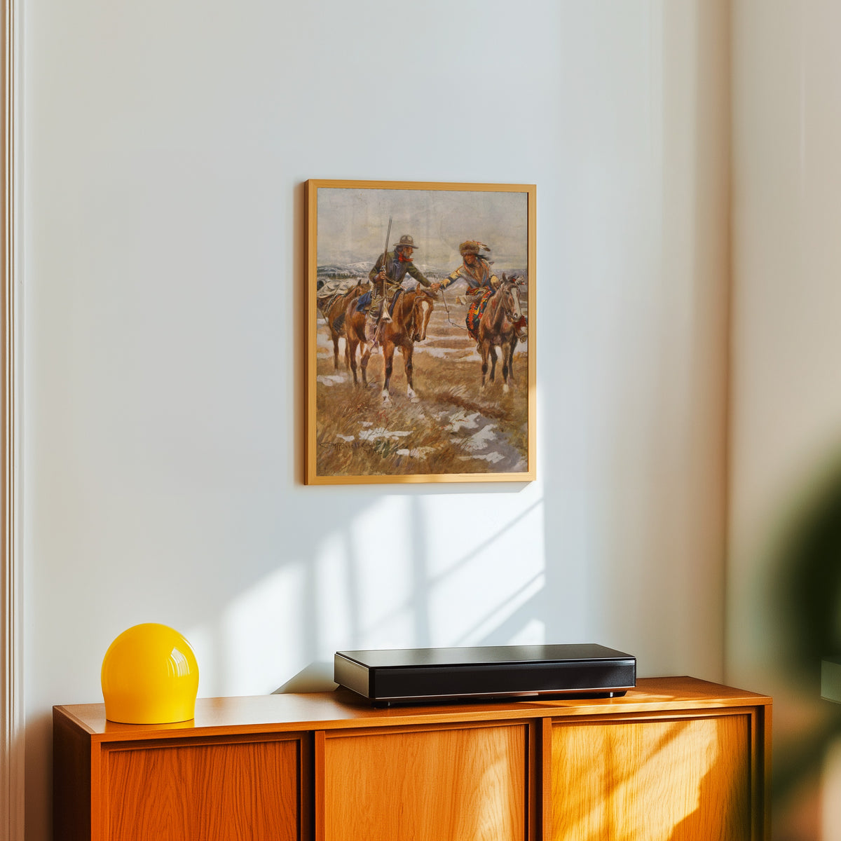 Framed art print of The Meeting by Charles M. Russell, in a light wood frame on a white wall above an orange sideboard