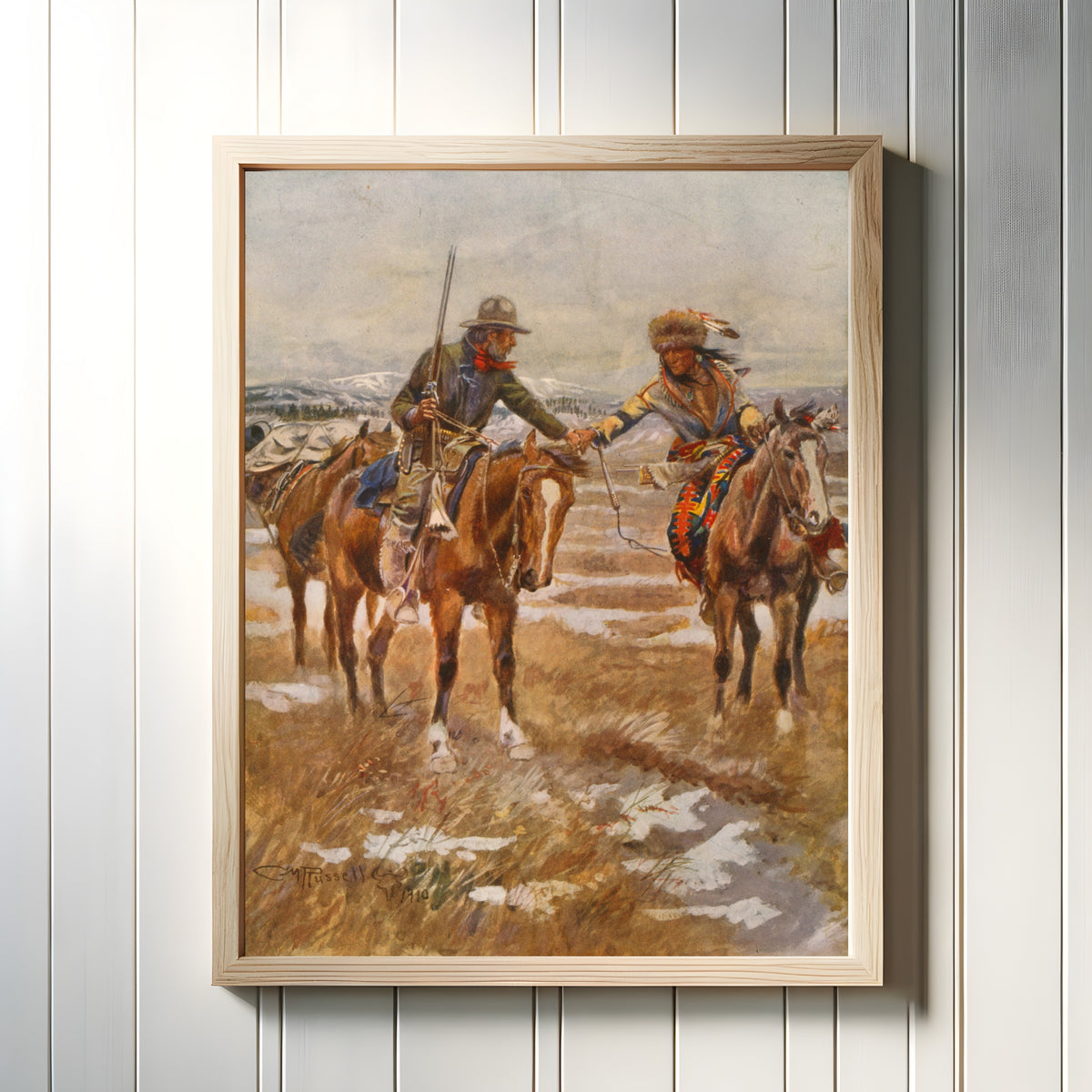 Framed art print of The Meeting by Charles M. Russell, in a light wood frame on a white panelled wall