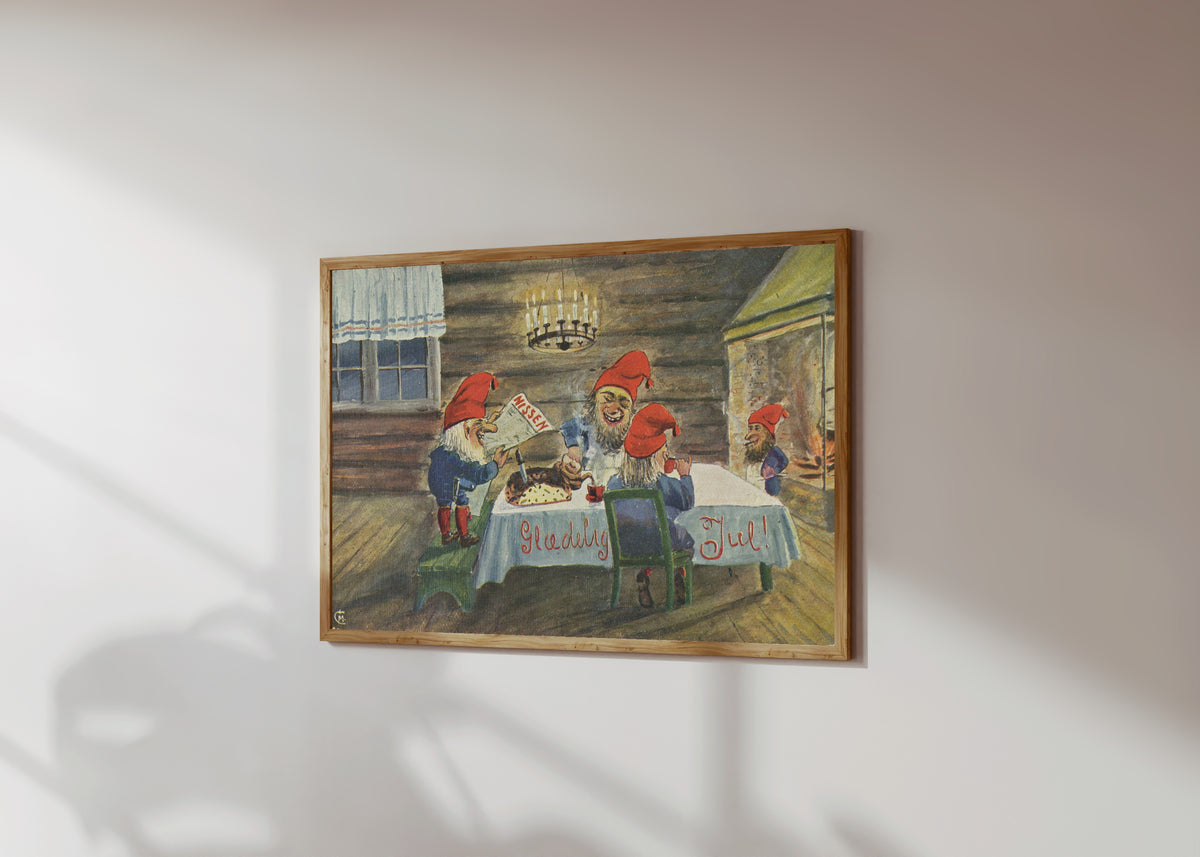 Framed art print of Gledelig Jul (Merry Christmas!) by Christian Magnus Moe, in a light wood frame on a sunlit white wall, seen at a slight angle