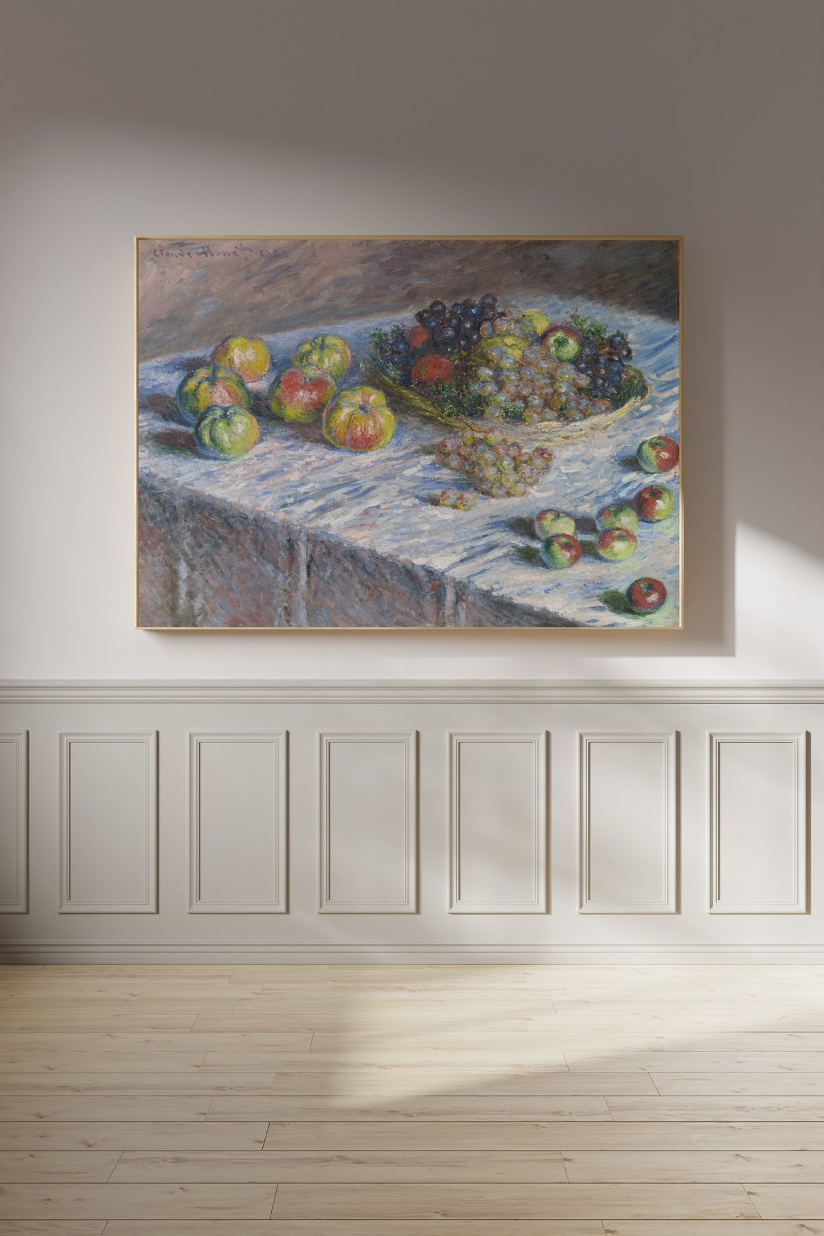 Apples and Grapes by Claude Monet — framed on a panelled wall in afternoon light