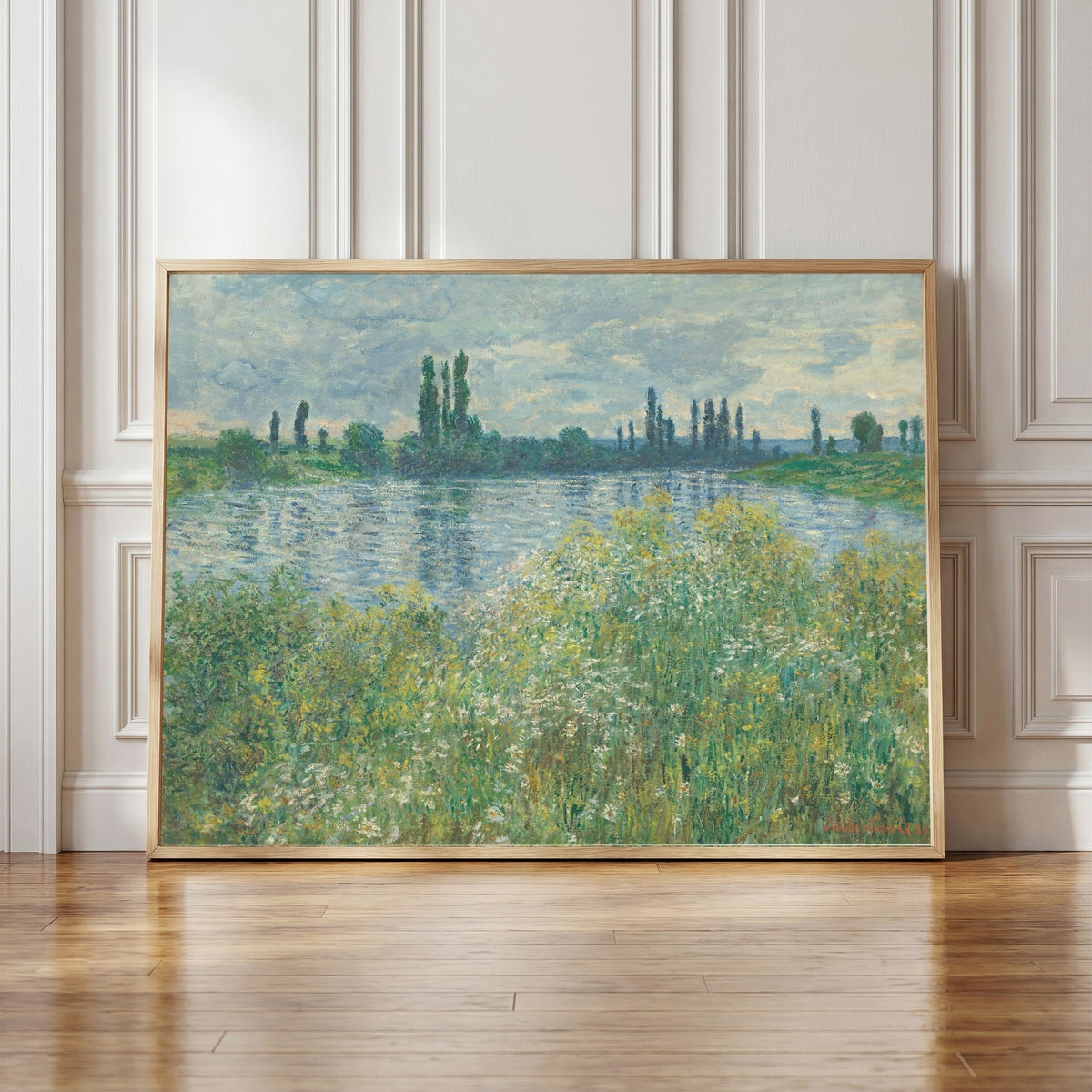 Framed art print of Banks of the Seine, Vetheuil by Claude Monet, in a light wood frame leaning against a panelled white wall