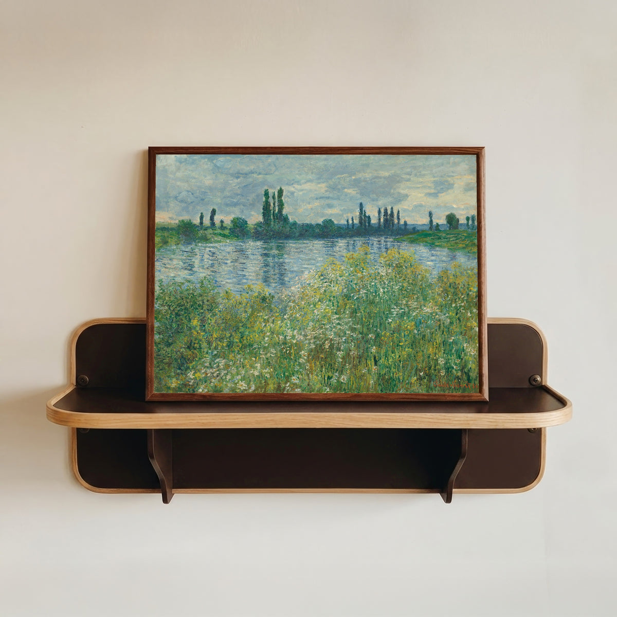 Framed art print of Banks of the Seine, Vetheuil by Claude Monet, in a dark wood frame resting on a wall shelf