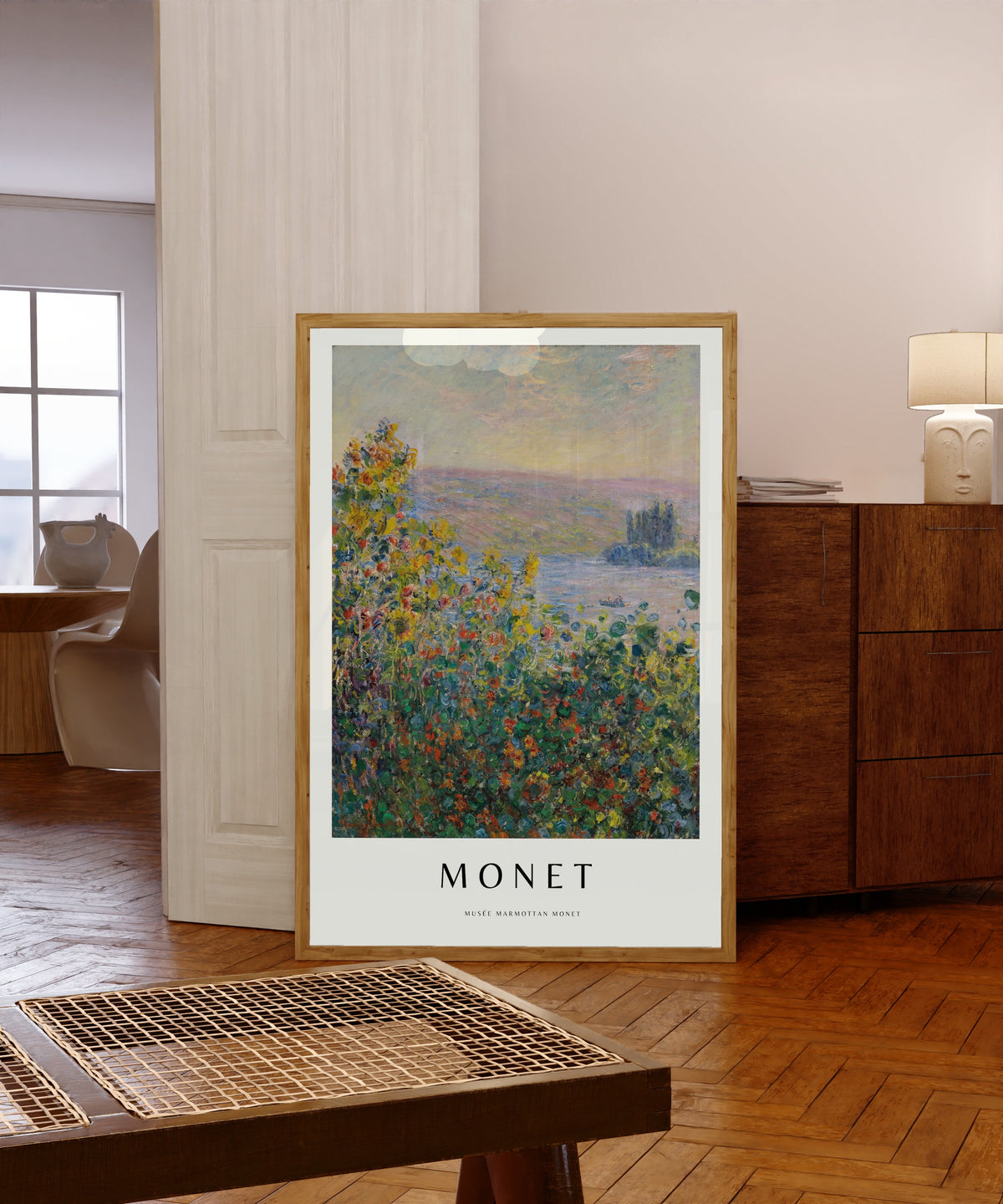 Framed art print of Flower Beds by Claude Monet, in a light wood frame leaning in a warm room with a parquet floor