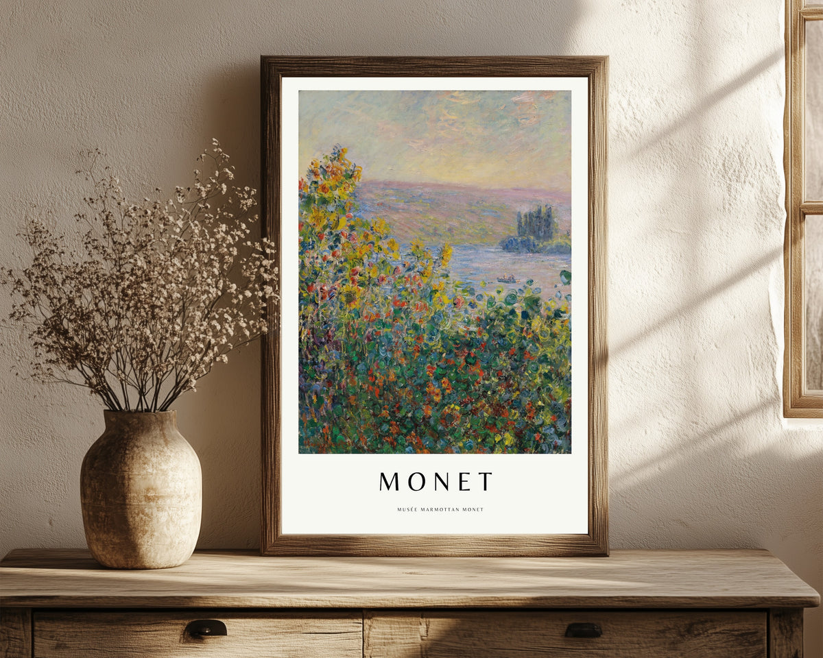 Framed art print of Flower Beds by Claude Monet, in a dark wood frame leaning on a rustic console beside dried flowers