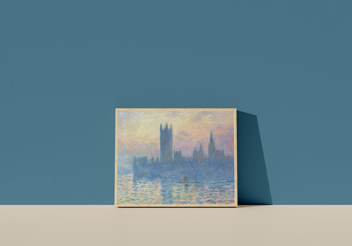 Framed art print of Houses of Parliament at Sunset by Claude Monet, in a light wood frame leaning on a blue wall
