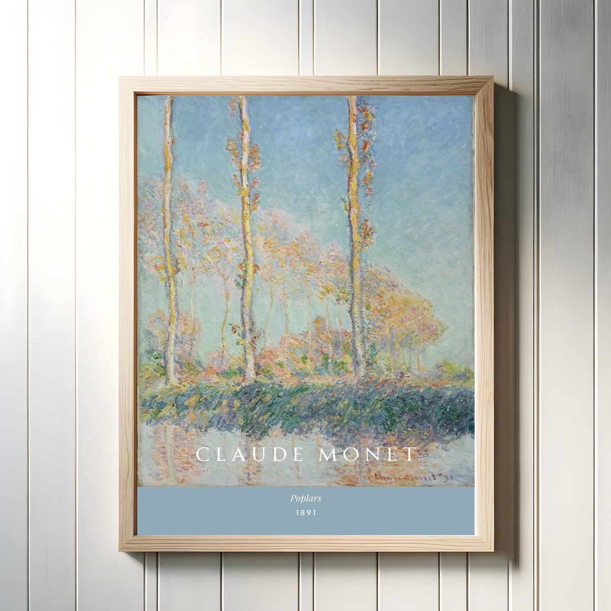 Framed art print of Poplars by Claude Monet, in a light wood frame on a white panelled wall