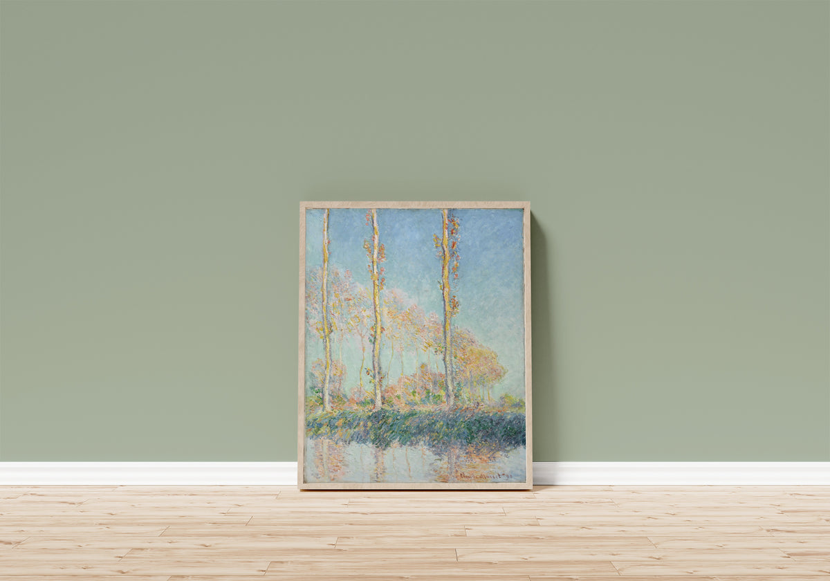 Framed art print of Poplars (Four Trees) by Claude Monet, in a light wood frame leaning on a sage green wall above a wooden floor