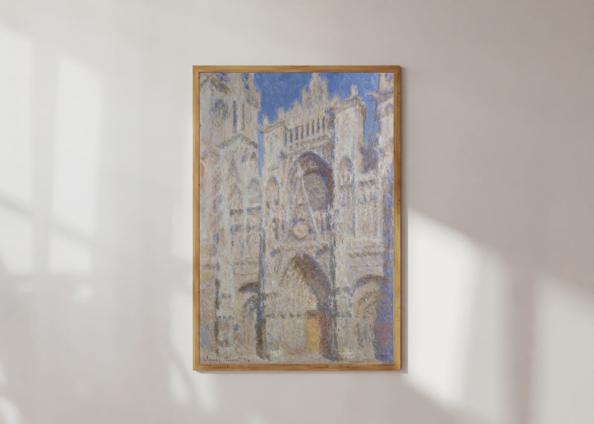 Framed art print of Rouen Cathedral, The Portal (Sunlight) by Claude Monet, in a light wood frame on a sunlit white wall
